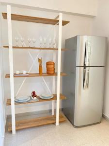 a shelf with glasses and a refrigerator in a kitchen at NuMa MAR in Puerto Madryn