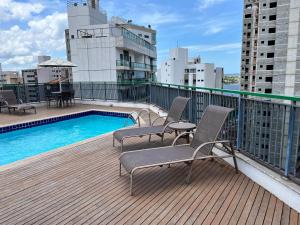 a balcony with chairs and a swimming pool on a building at Enseada do Suá Golden Gate - Moderno e Espaçoso in Vitória