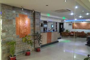 a lobby with potted plants and a living room at Hotel Crown in Rājshāhi