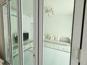 a white room with a mirror and a shelf with towels at Whitebeach Cottage in Chon Buri +7 photos