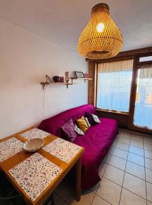 a living room with a purple couch and a table at Edelweiss Pila-Ski appartment con vista montagne in Pila +13 photos
