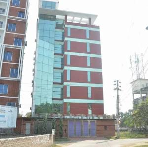 a tall red building with glass windows in front of it at Hotel Crown in Rājshāhi