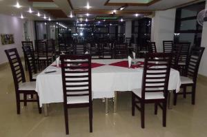 a dining room with a white table and chairs at Hotel Crown in Rājshāhi