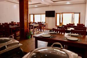 a dining room with wooden tables and chairs and windows at The Kun in Leh