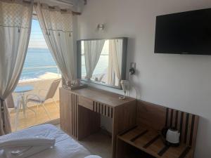 a bedroom with a mirror and a desk with a television at Hotel Beach Amaryllis in Megalochori