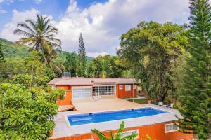 an orange house with a swimming pool and trees at Spacious Villa in La Cuaba, Pool in Pedro Brand