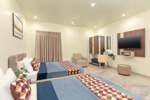 a hotel room with two beds and a flat screen tv at Greens Venue in Chennai