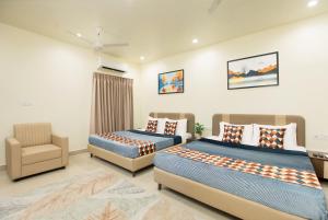 a bedroom with two beds and a chair in it at Greens Venue in Chennai