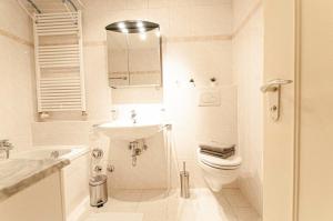 a white bathroom with a sink and a toilet at Ferienwohnung Steinfeldstrasse am Tegernsee in Rottach-Egern