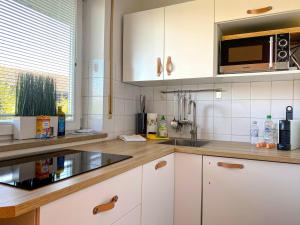 a kitchen with white cabinets and a microwave at Ferienwohnung Steinfeldstrasse am Tegernsee in Rottach-Egern