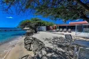 a table and chairs on a sandy beach next to the ocean at NEW RENOVATION - Beachside Two-Bedroom Suite in Savaneta