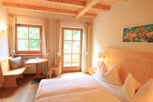 Un dormitorio con una cama y una mesa y ventanas. en Paalhof, en Castelrotto