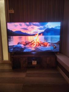 a flat screen tv with a fire in front of it at Le Cocon Du Lac in Nantua