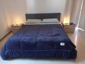 un grand lit avec une couette bleue et deux lampes dans l'établissement Monsoleil, à Reggio de Calabre