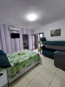 a living room with a bed and a couch at Pousada Nascimentos -Pé na Areia- À 47 Passos do Mar in Bertioga