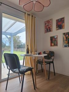 a dining room with a table and chairs and a window at La Pinède du Chéou, Piscine, Logement indépendant, Parking, Draps, Wifi fibre in Mimizan