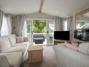 a living room with a couch and a tv at Eth Melyn Caravan Holiday in Grampound
