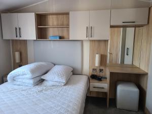 a bedroom with a bed with white sheets and cabinets at Eth Melyn Caravan Holiday in Grampound +19 photos