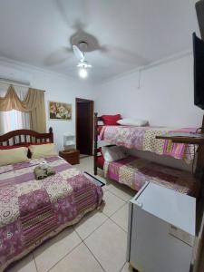 a room with three beds and a ceiling at Pousada Nascimentos -Pé na Areia- À 47 Passos do Mar in Bertioga