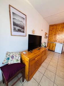 a living room with a television on a wooden cabinet at Edelweiss Pila-Ski appartment con vista montagne in Pila