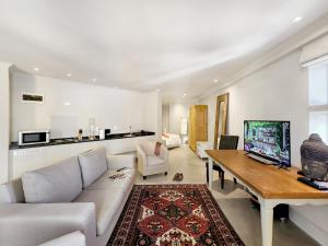 a living room with a couch and a table with a tv at Rouge on Rose Boutique Hotel in Cape Town