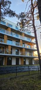 an apartment building with a tree in front of it at Apartament Sosnowy Las Widok na morze in Rowy