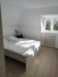 a white bedroom with a bed and a window at Ferienhaus Tätendorf für die ganze Familie in Tätendorf-Eppensen