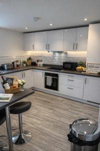 a large kitchen with white cabinets and a table at Palmiro Cottage in Lapford