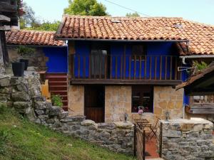 a blue house with a balcony and a stone wall at La Casina del Trasgu in Cangas de Onís +4 photos