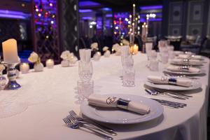 a long white table with plates and forks and napkins at Pensiunea Eden in Târgu Neamț