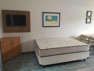 a bedroom with a bed and a flat screen tv at Beira mar Flat 2-209 in Ilhabela