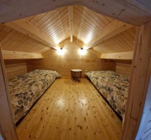 an attic room with two beds and a wooden floor at Vanagu priedes in Kalngale