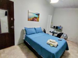 a bedroom with a bed with blue sheets and a table at Solares Aconchego - Suíte in Búzios +2 photos