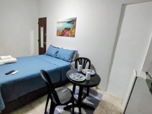 a small room with a bed and a table and chairs at Solares Aconchego - Suíte in Búzios