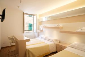a bedroom with two beds and a desk and a window at Hotel Melograno in Spotorno +161 photos