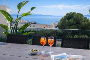 two glasses of wine sitting on a table on a balcony at Mare Vista Rooftop Penthouse Sea View & Private Jacuzzi in Trogir