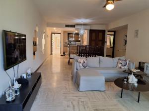 a living room with a white couch and a tv at Beachfront Portillo Residence in Las Terrenas