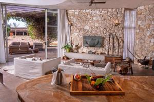 a living room with a couch and a tv on a stone wall at Casa del Toro Luxury Ranch in Nguékokh