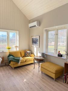 a living room with a yellow couch and windows at Idyllically nice house on Bjärehalvön, Torekov! in Båstad