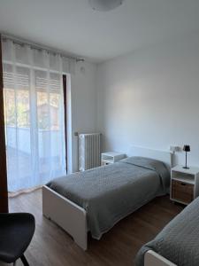 a white bedroom with two beds and a window at Casa Nello in Mergozzo