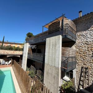 a building with a balcony and a swimming pool at le chemin des pouzes in Vallon-Pont-dʼArc