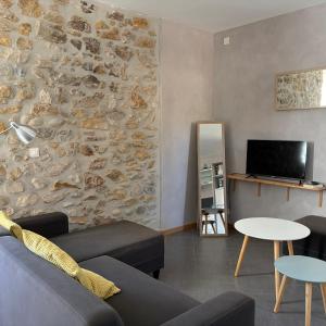 a living room with a couch and a tv at le chemin des pouzes in Vallon-Pont-dʼArc