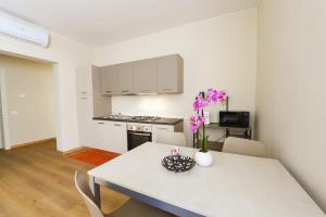 a kitchen and dining room with a white table with purple flowers at Affittacamere Marilù in Paratico