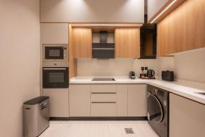 a kitchen with white cabinets and a washer and dryer at Rozn Place Apartments in Jeddah