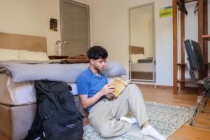 a man sitting on the floor reading a book at Rafiki Hostels - Pyramids in Giza
