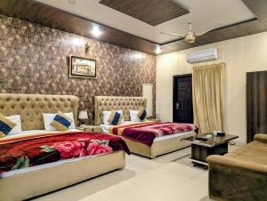 a bedroom with two beds and a couch at Royal Fort Executive Hotel Gulberg in Lahore +18 photos
