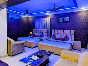 a hotel room with two beds and a couch at Royal Fort Executive Hotel Gulberg in Lahore