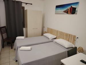 a room with two beds and a chair and a picture at Affittacamere la Medusa in Porto Pino