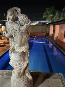 a statue of a woman holding a child next to a swimming pool at Villa Di Verona Charm Hotel in Guarujá
