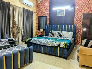 a bedroom with a blue bed and a chair at Royal Fort Executive Hotel Gulberg in Lahore